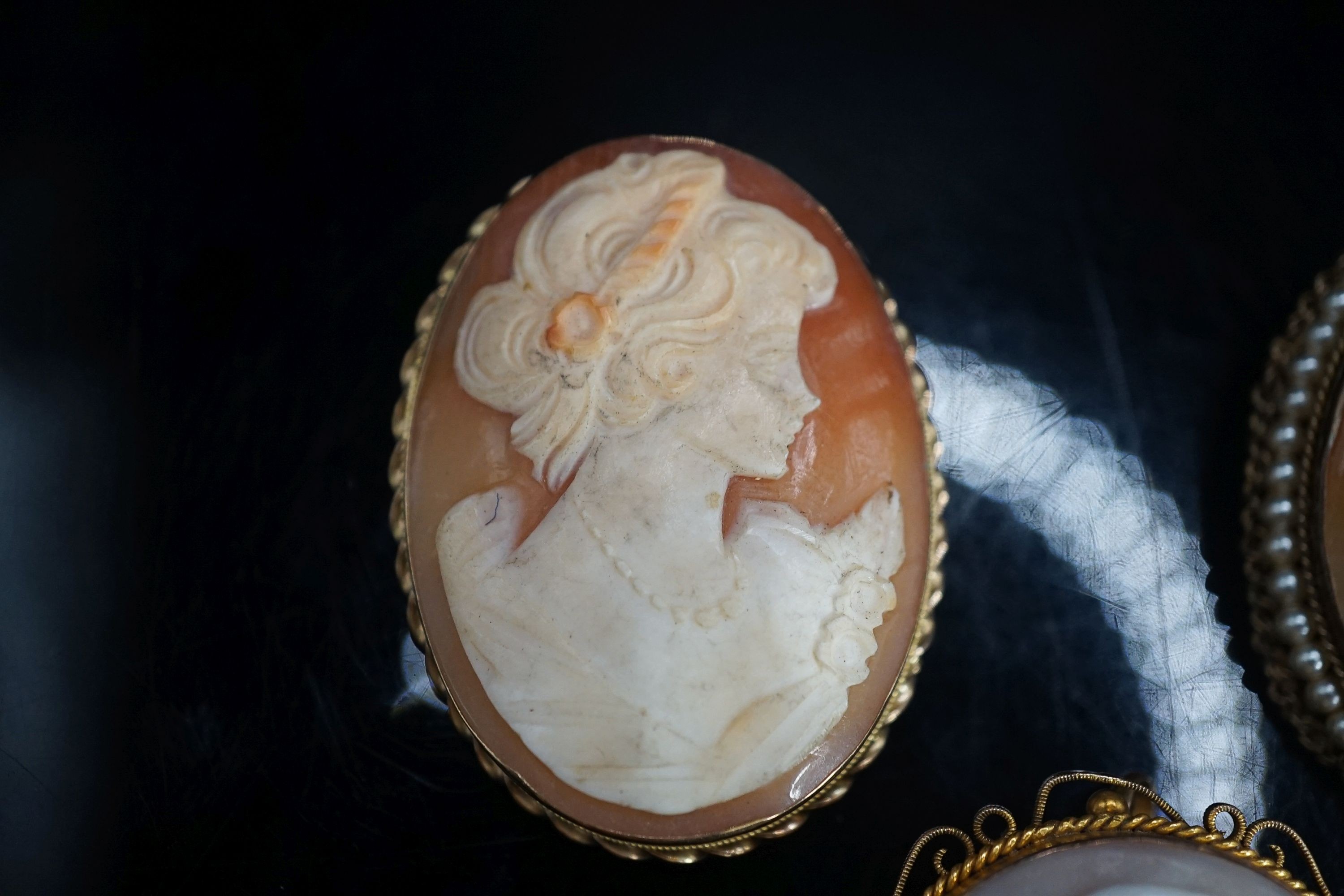 A Victorian 9ct mounted oval cameo shell brooch, one other later 9k mounted cameo brooch and a gilt metal mounted cameo brooch.